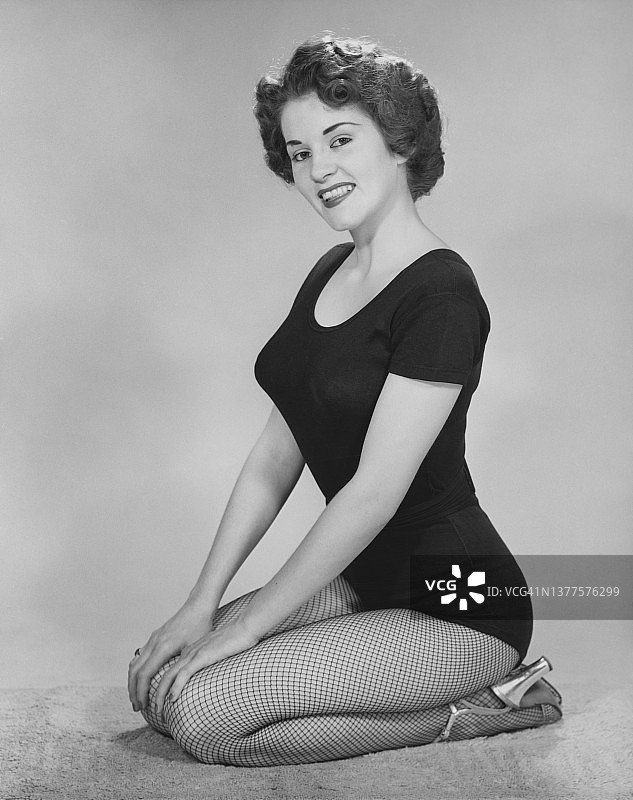 女人跪着，穿着紧身衣、渔网袜和银色高跟鞋图片素材