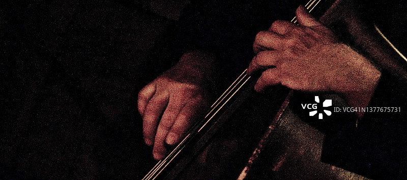 在低音提琴琴颈上的颗粒感双手图片素材