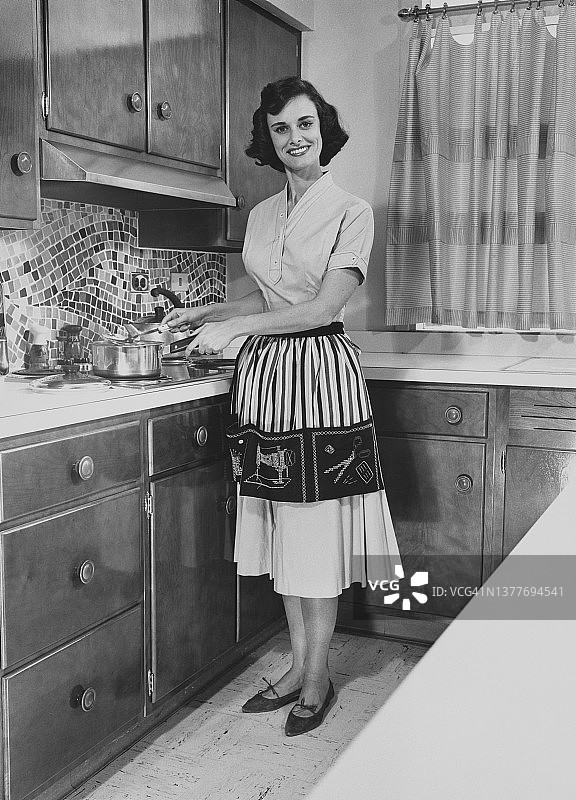 系着围裙在炉灶上烹饪的女人图片素材