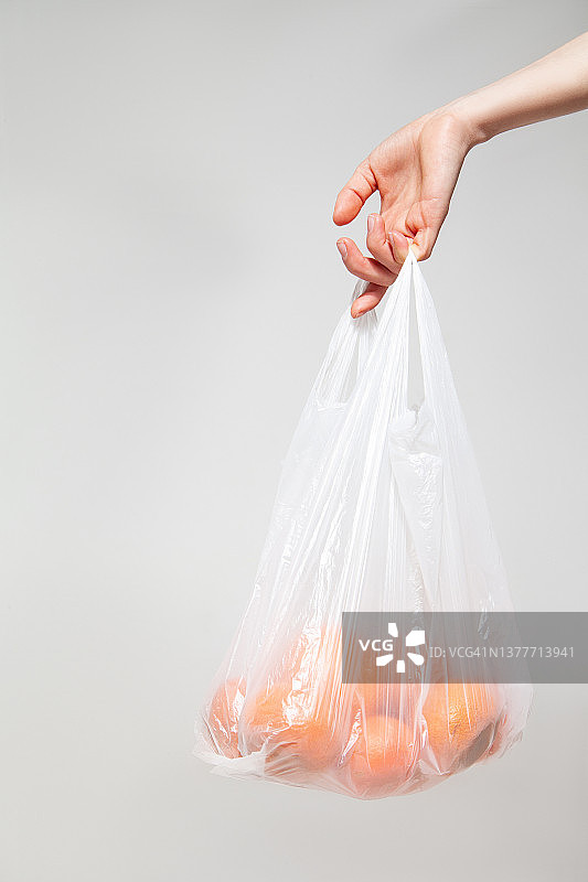 女人提着装满橘子的塑料袋图片素材