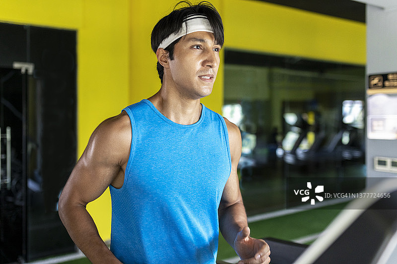 男子在健身房跑步机上跑步图片素材
