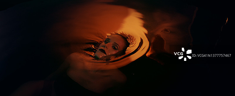 水下冥想：迷人的女人从金色水域中浮现图片素材