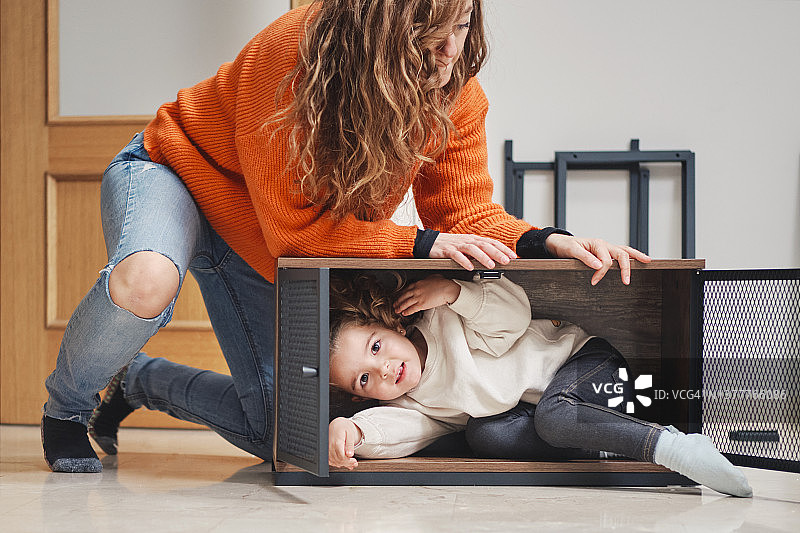 女孩躲在妈妈组装的家具里图片素材