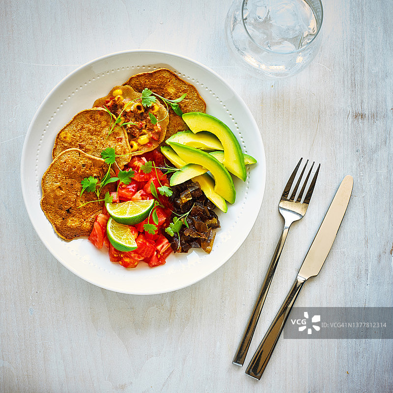 甜玉米红辣椒油炸馅饼配番茄、鳄梨、枣图片素材