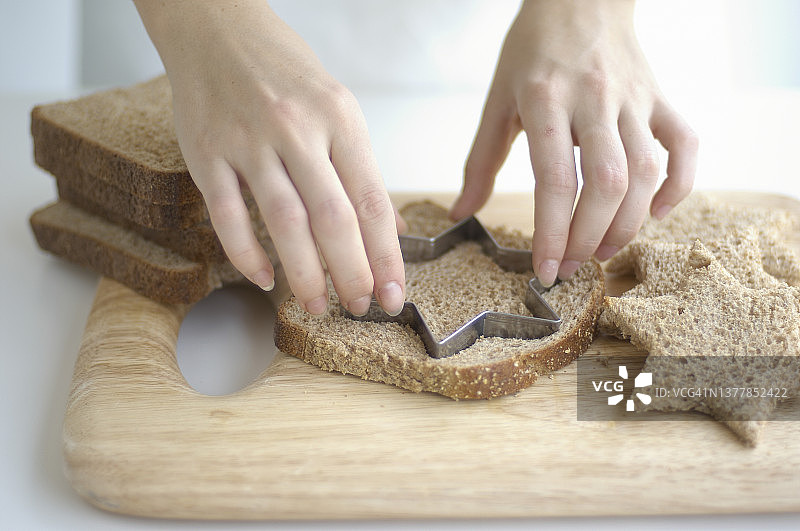 手持糕点切割器，从全麦面包中切出星星图片素材