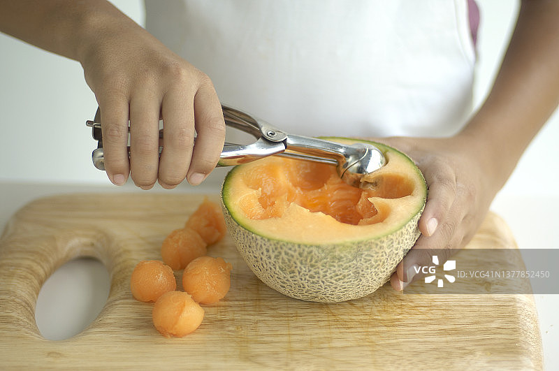 手持挖球器从哈密瓜中取出瓜球图片素材