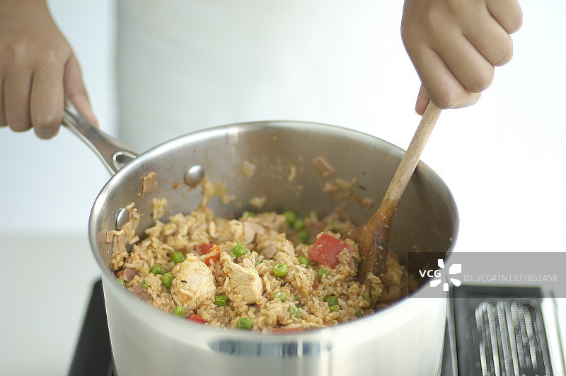 手持木勺在平底锅中搅拌什锦饭图片素材