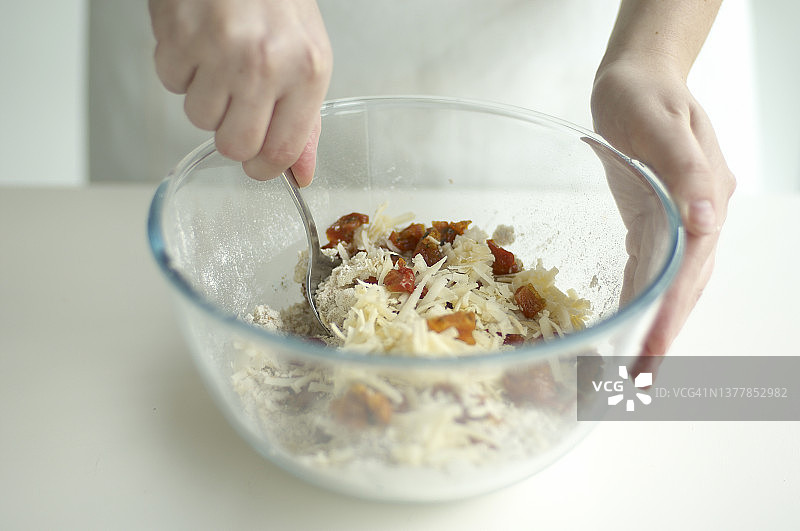 手持勺子搅拌碗中咸味烤饼混合物图片素材