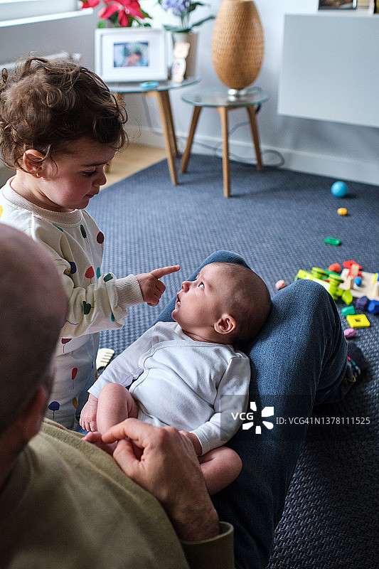 父亲抱着男婴，另一个孩子看着他并和他一起玩耍图片素材