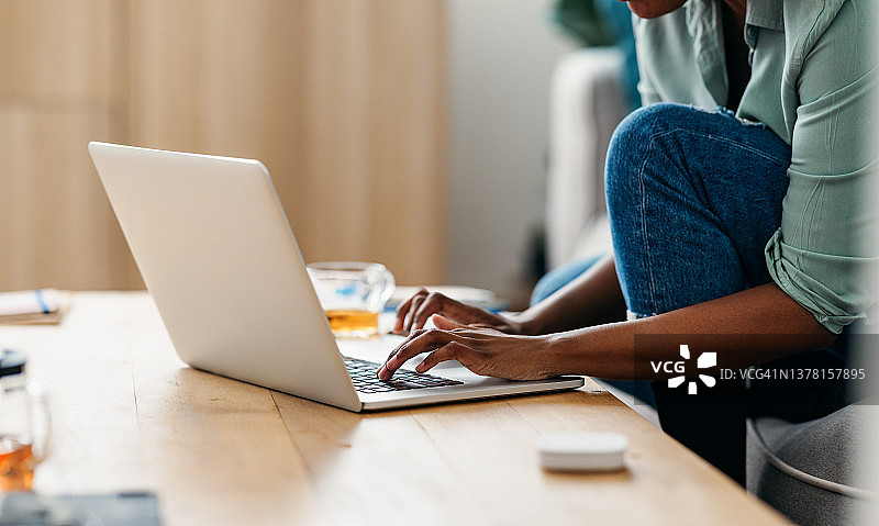 家庭办公室：匿名非裔美国妇女在笔记本电脑上打字图片素材