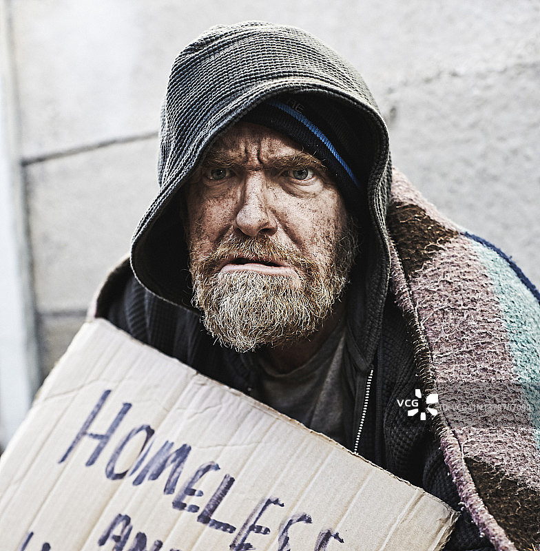 举着纸板标志乞讨的无家可归者愤怒地盯着镜头图片素材