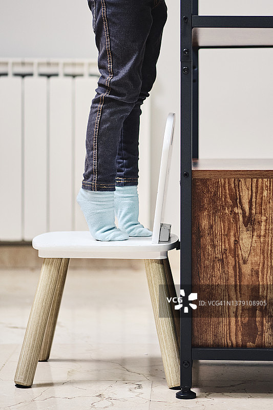 站在椅子上踮起脚尖的小女孩图片素材