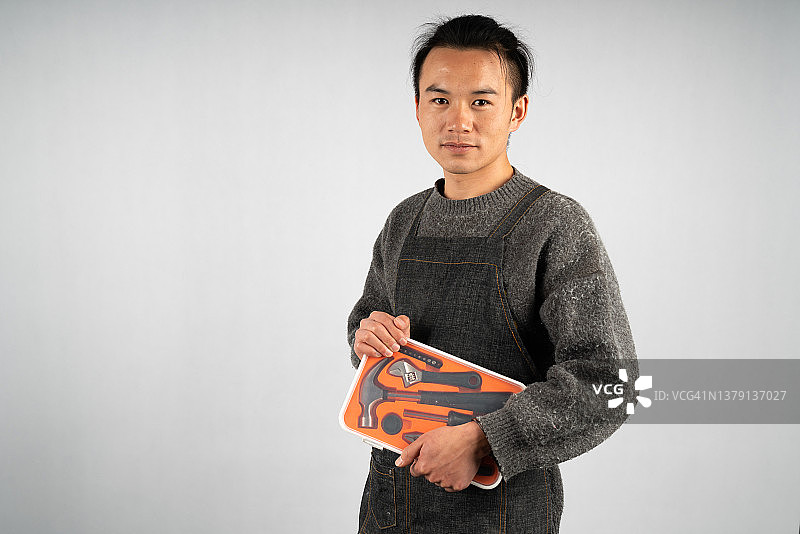 年轻亚洲男性技工手持工具箱白色背景图片素材