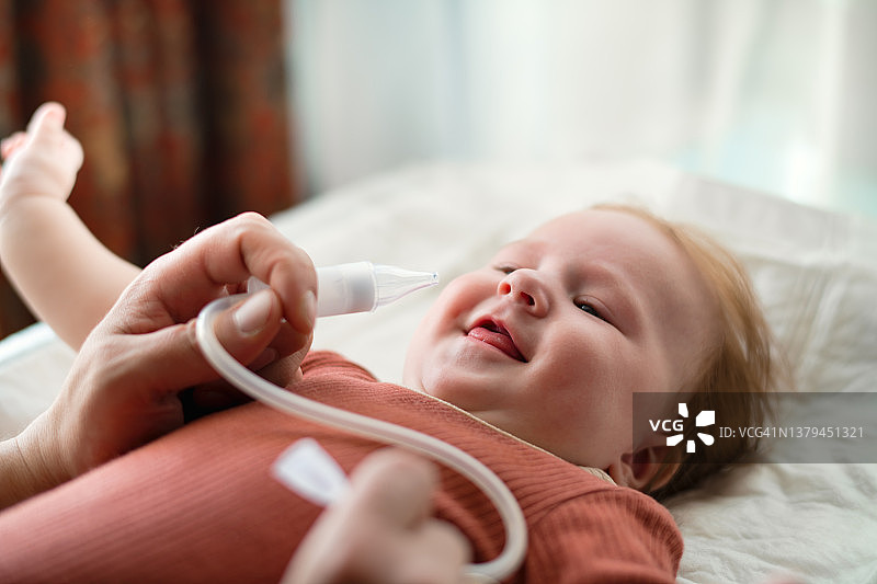 男子在家用吸鼻器为女婴清理鼻腔图片素材