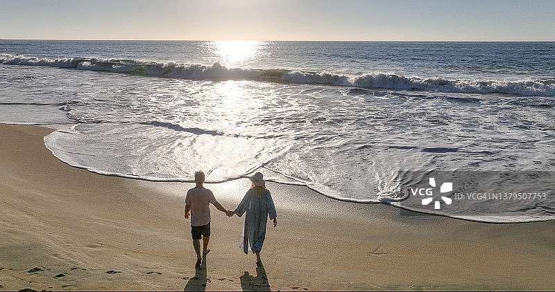 航拍一对中年夫妇在海滩上散步图片素材