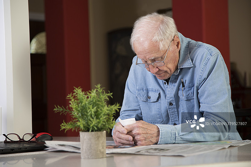 在厨房吧台阅读报纸的白人男子图片素材