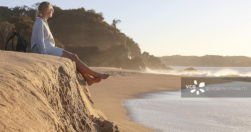 中年妇女在海滩上放松，眺望大海图片素材