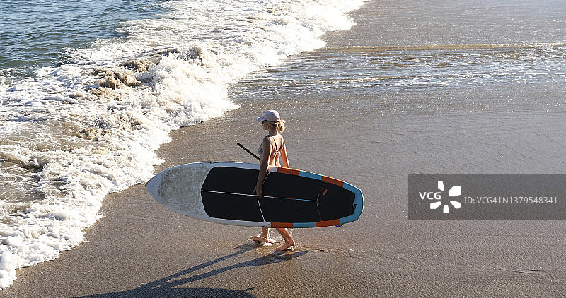 女子桨板冲浪后走下海滩图片素材