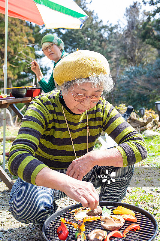 日本年长女士在烧烤上烤蔬菜图片素材