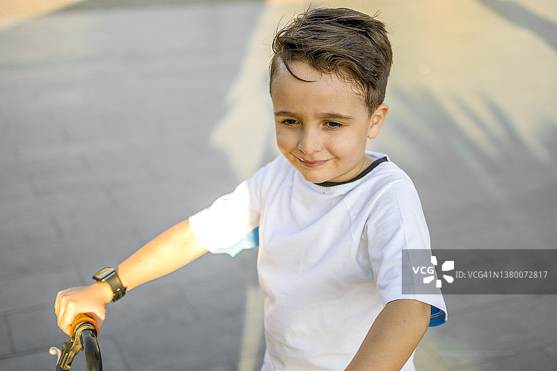 英俊的小男孩骑自行车去公园图片素材