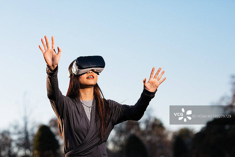 年轻女人在户外使用VR头显设备体验虚拟现实图片素材