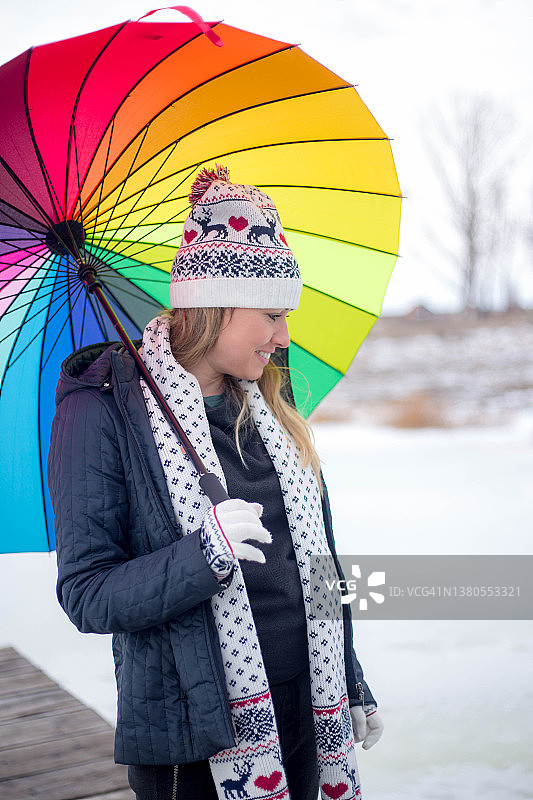 撑着彩虹伞在雪地里享受的女人图片素材