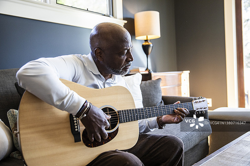 年长的男人在家弹奏原声吉他图片素材