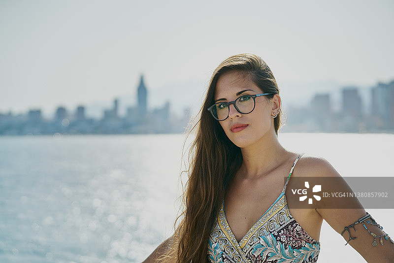 阳光明媚的日子里，长发美女在贝尼多姆市的地中海背景下看着镜头图片素材