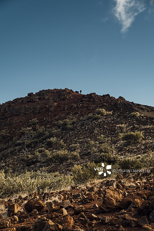 一个人在沙漠般的山地上向地平线徒步图片素材