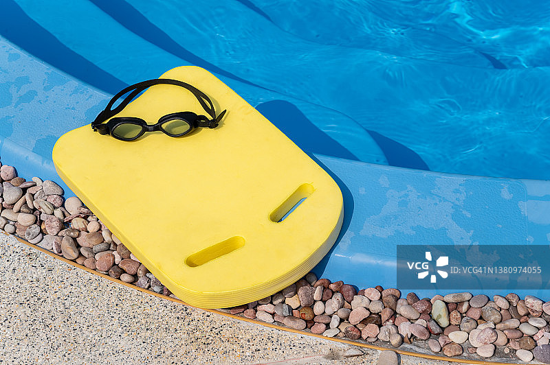 游泳池边的黄色游泳板和泳镜图片素材