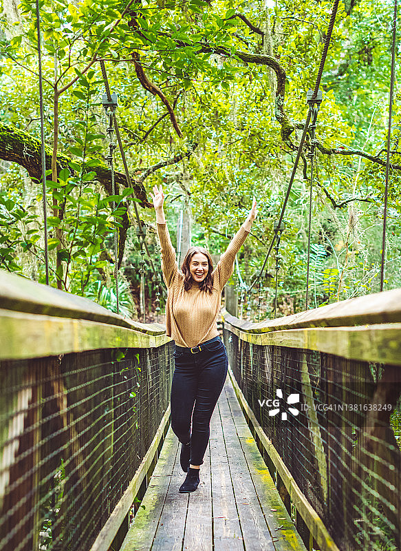 在热带雨林异国度假中走过桥的激动女人图片素材