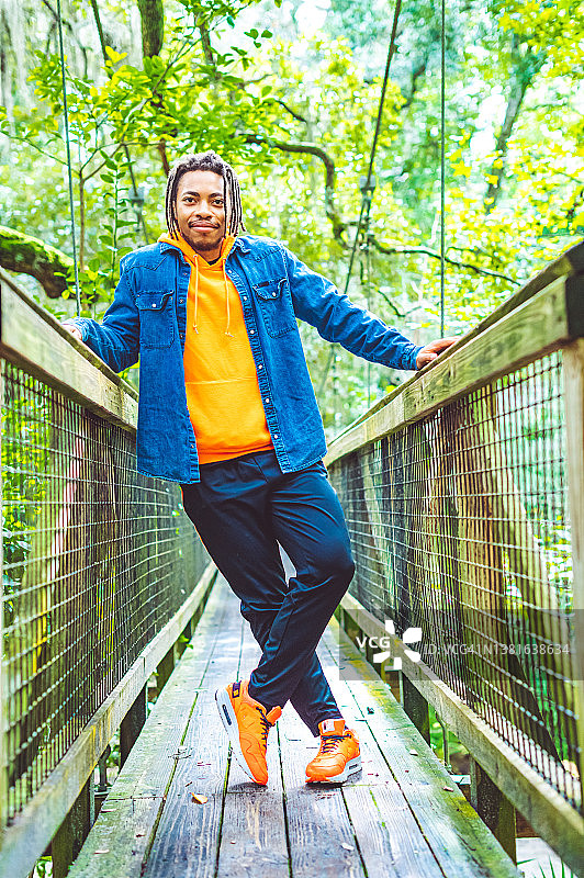 在热带雨林风景桥上摆姿势的快乐年轻黑人男子异国旅行冒险图片素材