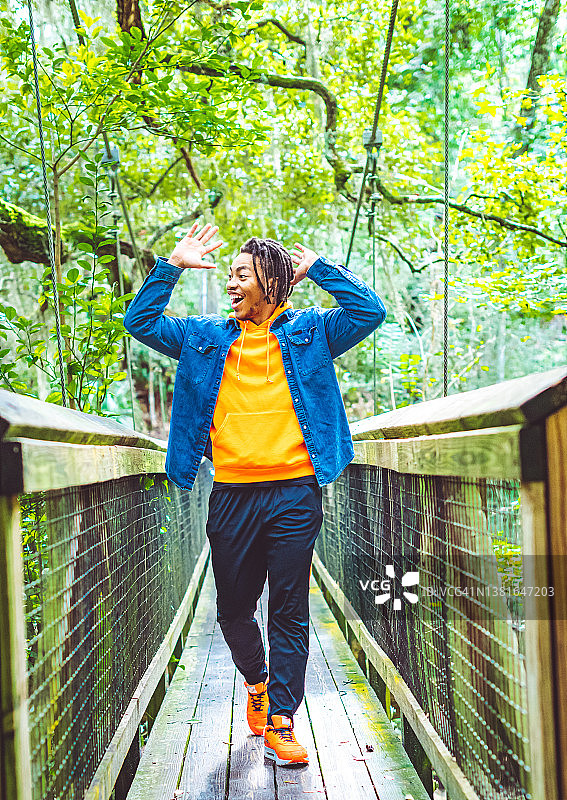 在热带雨林风景桥上摆姿势的快乐年轻黑人男子异国旅行冒险图片素材