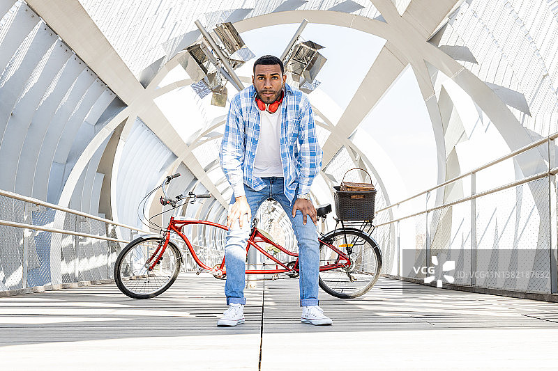 一位年轻人站在双人自行车后面，向前倾斜，等待着什么图片素材