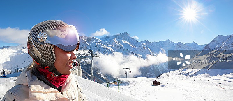 戴着滑雪头盔在滑雪坡上的混血女人图片素材