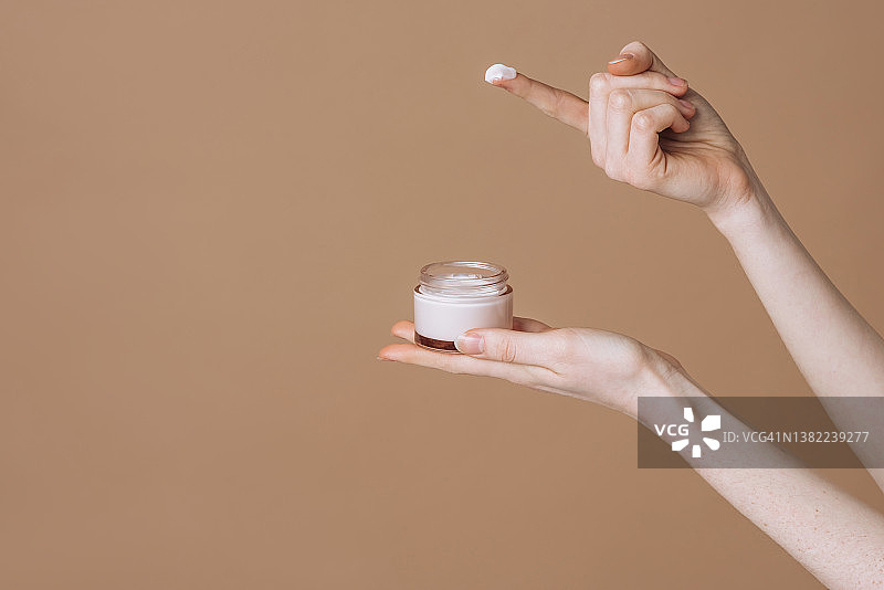 手持塑料罐装面霜特写图片素材