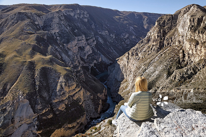 金发女人坐在岩石上欣赏风景图片素材