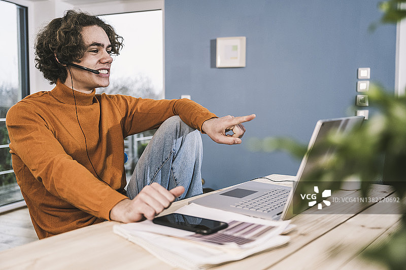 面带微笑的年轻学生在家中通过笔记本电脑参加视频通话图片素材