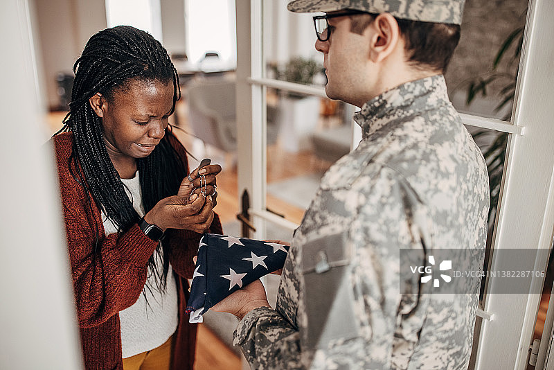 士兵将叠好的美国国旗带给家中的遗孀，告知她丈夫在战争中牺牲图片素材