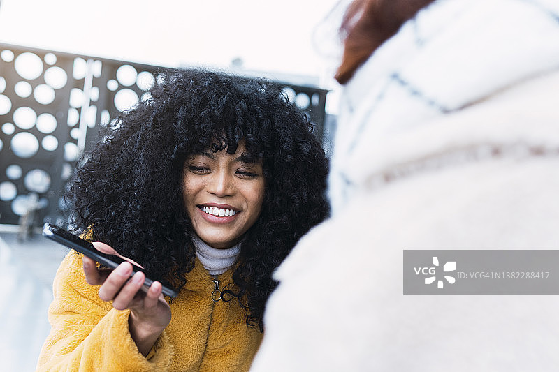 与朋友分享手机的微笑女人图片素材