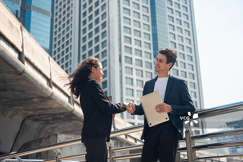 在现代办公室外握手的男女商人图片素材