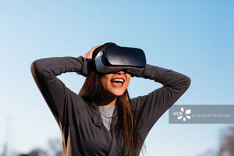 戴着VR眼镜，抱着头的年轻女人图片素材