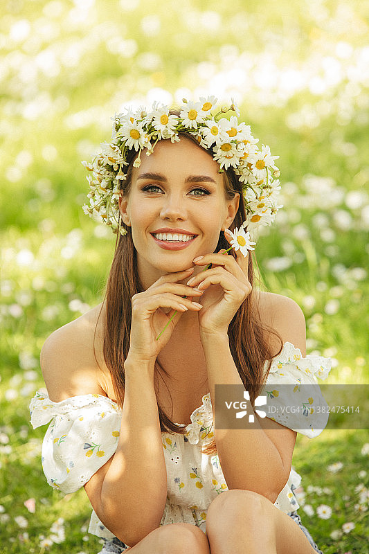 微笑的年轻女子坐在草地上图片素材