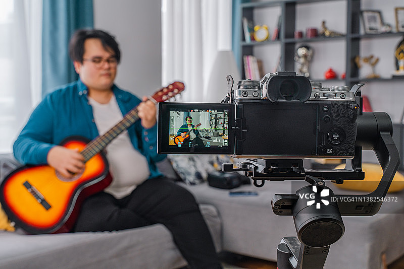 在家拍摄视频和对着镜头弹吉他的超重男孩图片素材