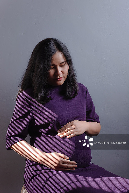 怀孕的女人在影棚里抚摸肚子图片素材