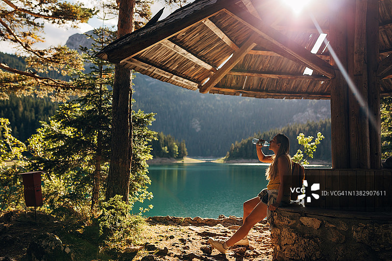 千禧一代女性在自然小屋旁休息的侧面照图片素材