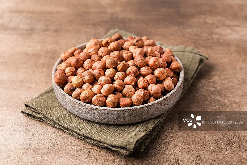 盘子里的榛子，棕色桌子，超级食品。图片素材