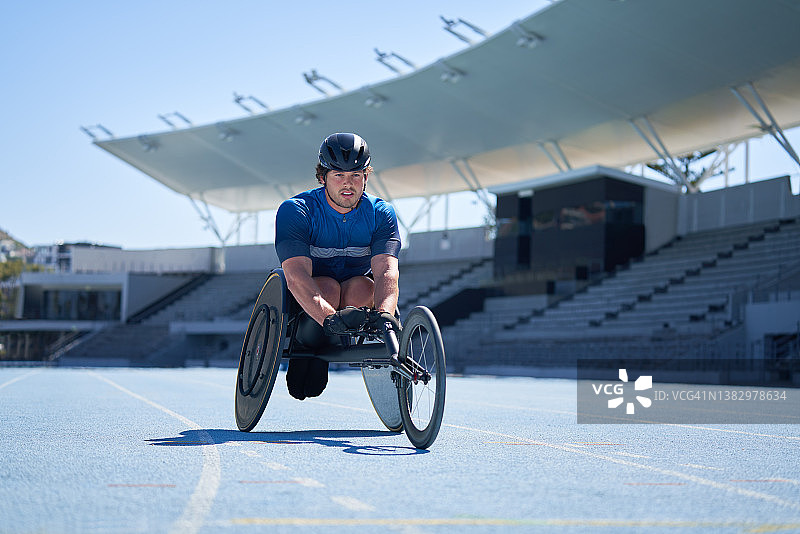 阳光明媚的蓝色跑道上的轮椅男运动员图片素材