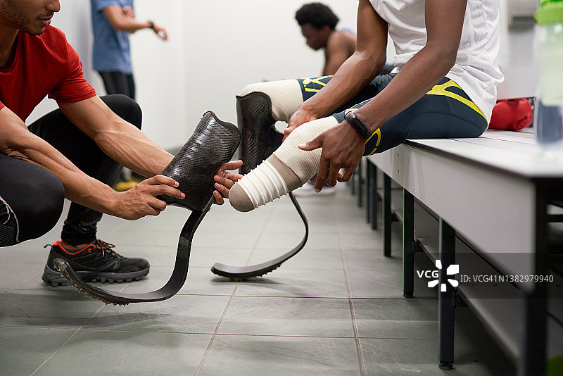 教练帮助安装跑步刀锋假肢的男子截肢运动员图片素材