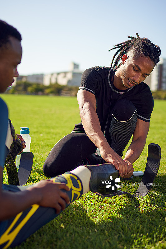 教练在公园帮助年轻的截肢运动员使用假肢图片素材